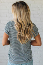 Blonde woman wearing a charcoal grey and white horizontal striped tee with a twist back keyhole accent across the back shoulders.