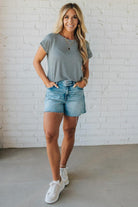 Blonde woman wearing a charcoal grey and white horizontal striped tee with a twist back keyhole accent across the back shoulders.