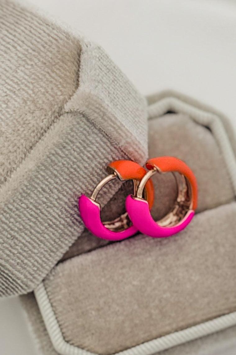 Pair of colorful hoop earrings on a textured surface