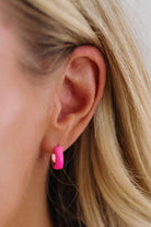 Close-up of an ear wearing a pink earring with a blurred background
