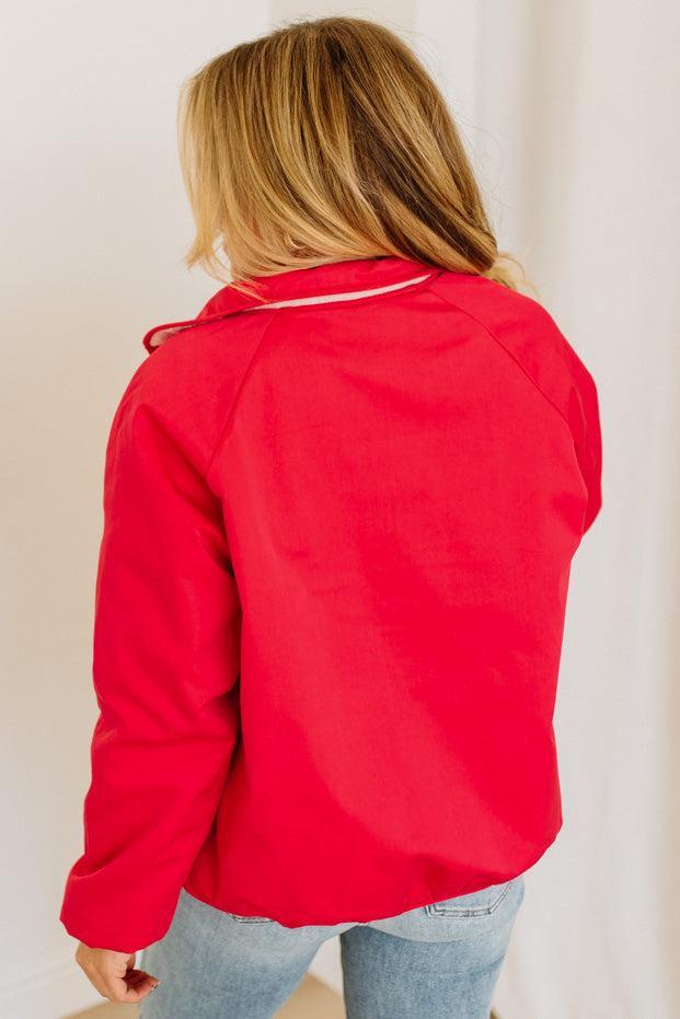 Person wearing a red jacket from behind with a plain background