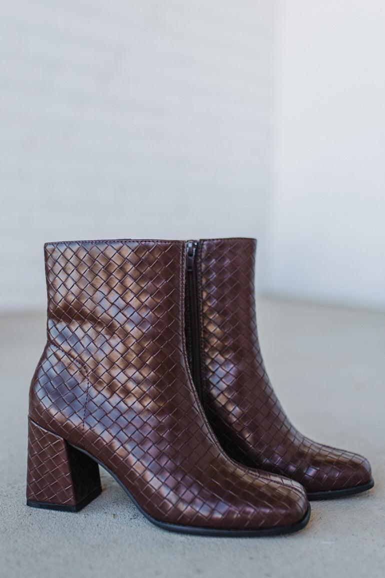 Pair of brown woven ankle boots on a light gray background