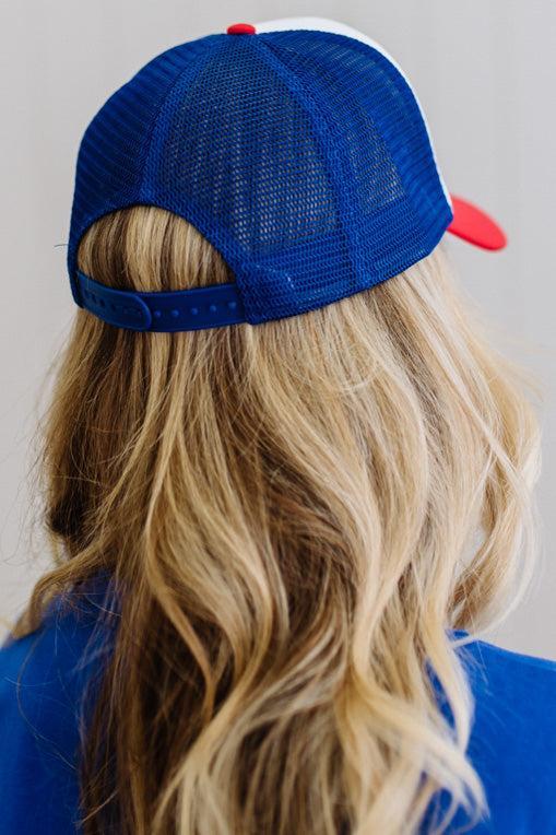 Person wearing a blue and red cap with long blonde hair