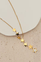 Gold star necklace on a beige surface with a white plate in the background