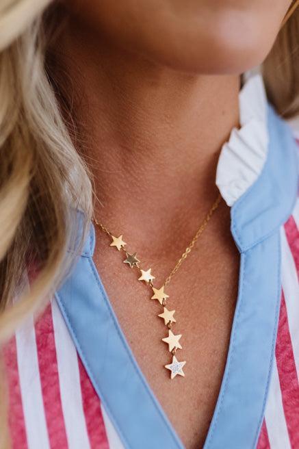 Gold star necklace worn by a person with a striped shirt