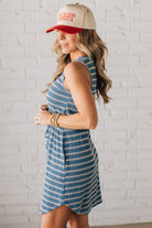 Blonde woman in a hat wearing a V-NECK, FAUX BUTTON UP, ELASTIC WAIST TIE, STRIPE DRESS WITH RIBBED TEXTURE knee length dress.