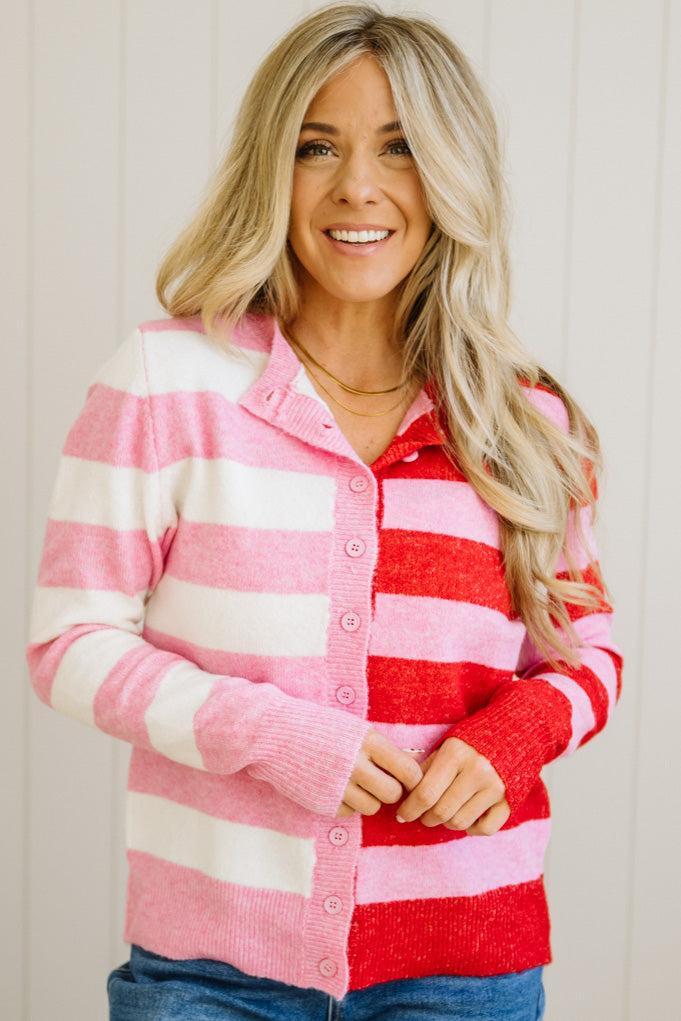 Woman wearing a pink and red striped cardigan against a plain background