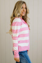 Woman wearing a pink and white striped sweater against a beige wall.