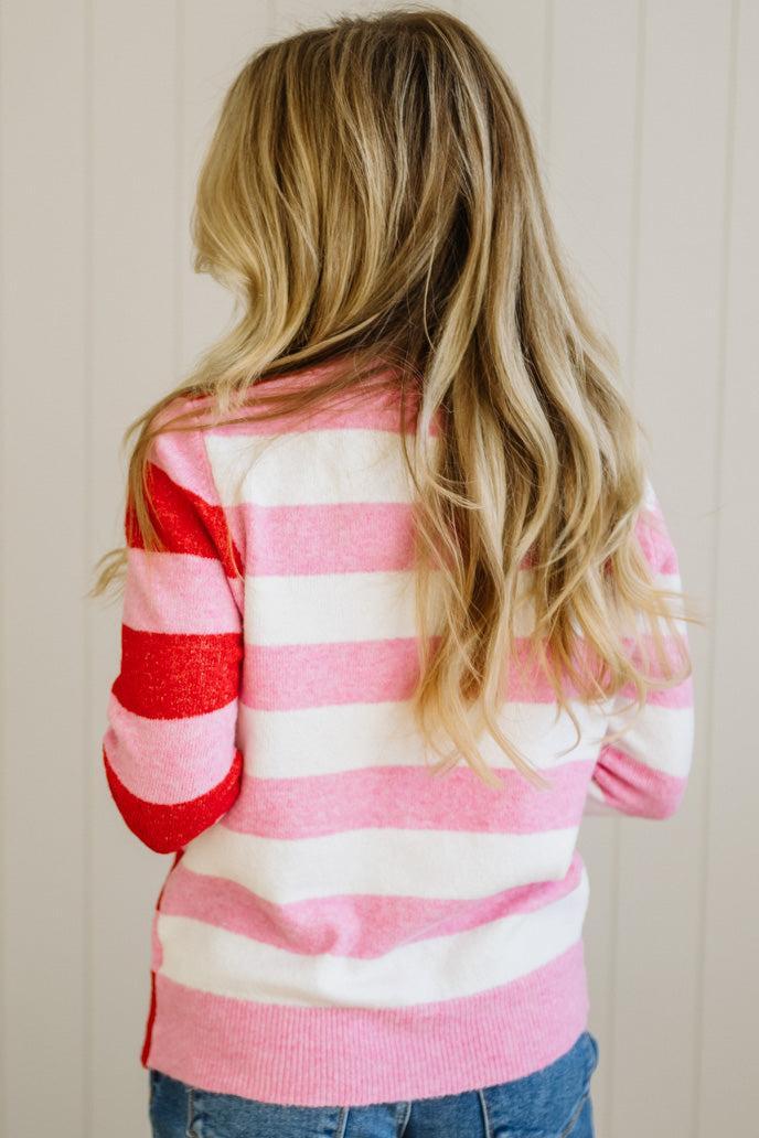 Person wearing a pink and white striped sweater with a neutral background