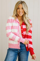 Woman wearing a pink and red striped cardigan with blue jeans against a neutral background