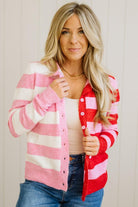 Woman wearing a red and pink striped cardigan over a white top and blue jeans.