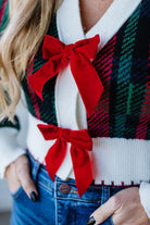 BLONDE WOMAN WEARING A VELVET BOW RIBBON EMBELLISHED CHRISTMAS CHECKER PLAID BUTTONED SWEATER CROP CARDIGAN