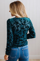 BLONDE WOMAN IN DARK JEANS WEARING A ROMANTIC VELVET BURNOUT TOP WITH FEATURES LIKE, BURNOUT VELVET MESH FABRICATION, SCALLOPED LACE EDGE ACCENTS, FUNCTIONAL BUTTONS AND LONG SLEEVES