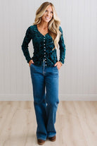BLONDE WOMAN IN DARK JEANS WEARING A ROMANTIC VELVET BURNOUT TOP WITH FEATURES LIKE, BURNOUT VELVET MESH FABRICATION, SCALLOPED LACE EDGE ACCENTS, FUNCTIONAL BUTTONS AND LONG SLEEVES