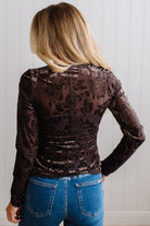 BLONDE WOMAN IN DARK JEANS WEARING A ROMANTIC VELVET BURNOUT TOP WITH FEATURES LIKE, BURNOUT VELVET MESH FABRICATION, SCALLOPED LACE EDGE ACCENTS, FUNCTIONAL BUTTONS AND LONG SLEEVES