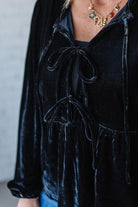 Black velvet jacket with drawstring details on a neutral background