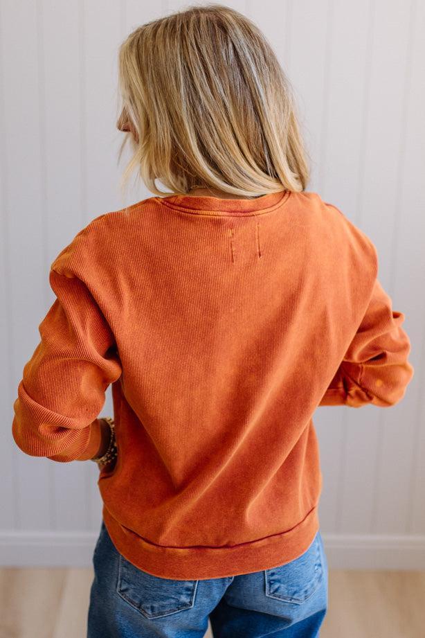 Blonde woman wearing a rust orange colored corduroy sweatshirt 