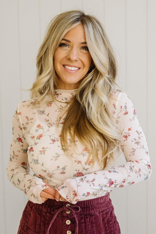 Woman wearing a floral long-sleeve top against a plain background