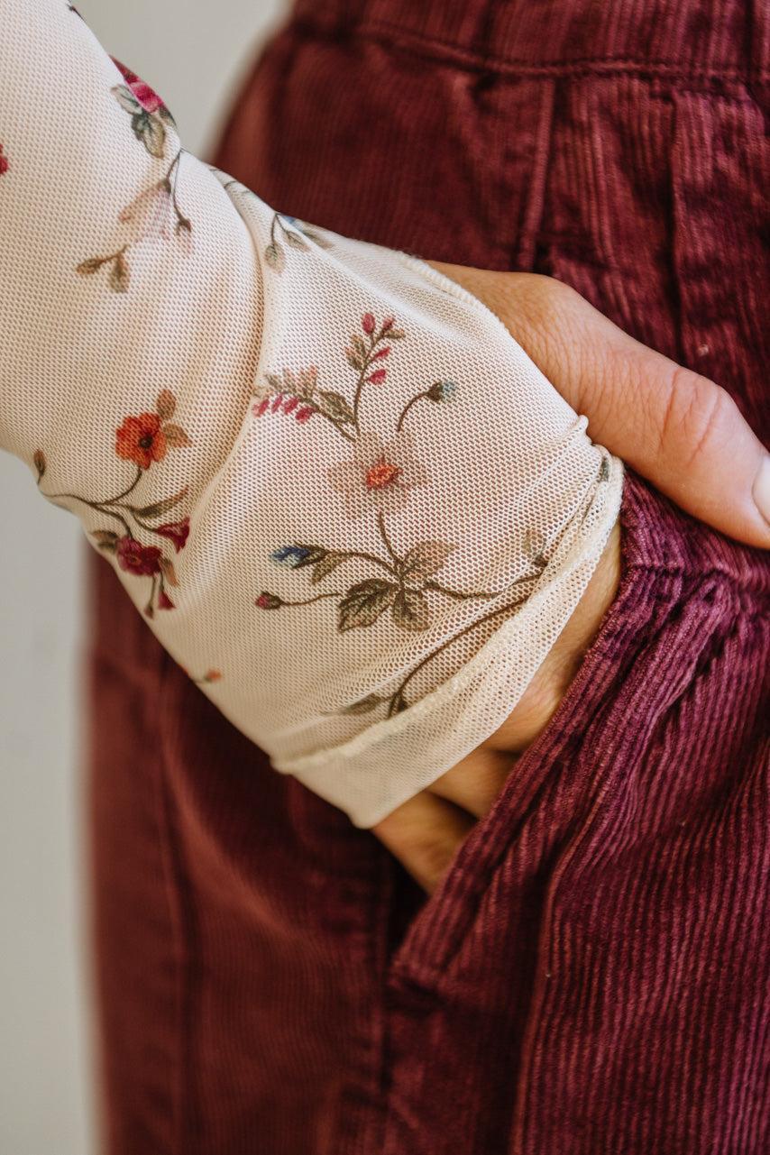 Close-up of a hand wearing a floral sleeve with a blurred background