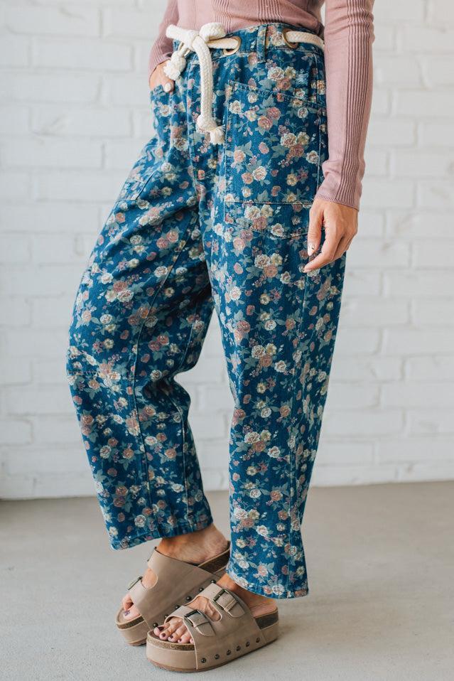 Person wearing blue floral pants with a white brick wall background