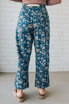 Person wearing blue floral pants against a white brick wall.