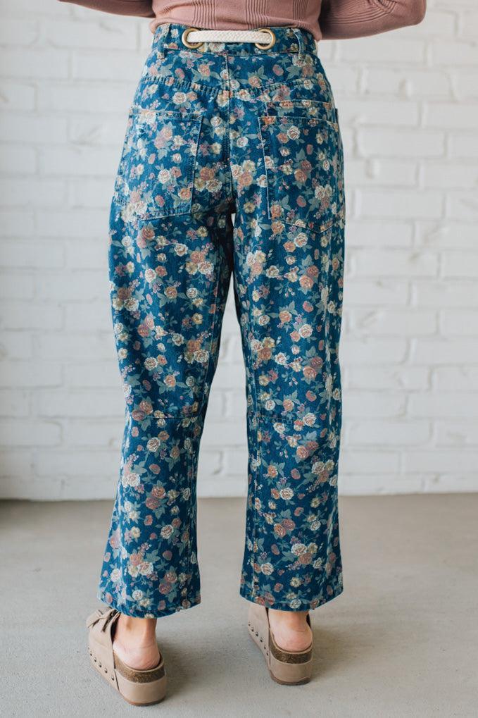 Person wearing blue floral pants against a white brick wall.