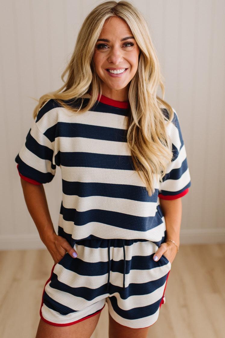 Woman wearing a navy and white striped outfit with red accents indoors.