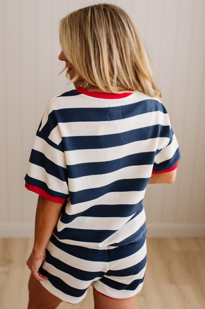 Person wearing a navy and white striped outfit with red accents.