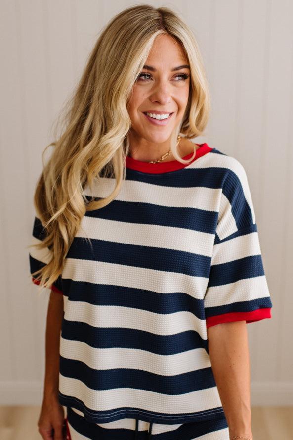 Woman wearing a striped shirt with navy, white, and red colors against a neutral background