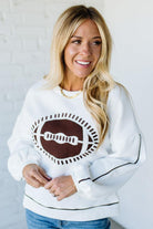 Woman wearing a white sweatshirt with a brown graphic design against a white background