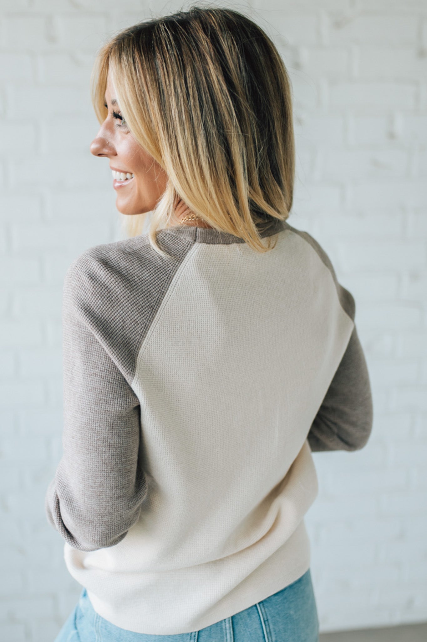 Woman wearing a two-tone sweater against a light background