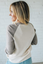 Woman wearing a two-tone sweater against a light background