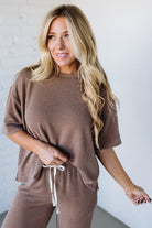 Woman wearing a brown ribbed lounge set against a white background