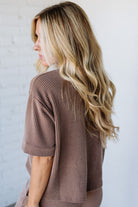 Woman wearing a brown ribbed sweater against a light background