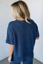 Person wearing a blue ribbed sweater and pants against a white wall