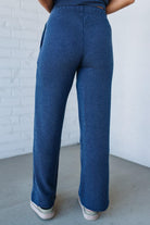 Person wearing blue ribbed pants against a white brick wall.