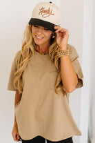 Woman wearing a beige cap and oversized t-shirt against a white background
