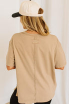 Person wearing a beige t-shirt and cap from behind on a white background