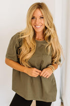 Woman wearing an olive green t-shirt with a plain background