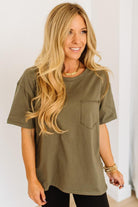 Woman wearing an olive green t-shirt with a plain background