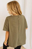 Person wearing an olive green t-shirt with a plain background