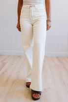 Person wearing white pants on a light wooden floor with a white wall background