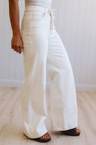 Person wearing white wide-leg jeans on a plain background