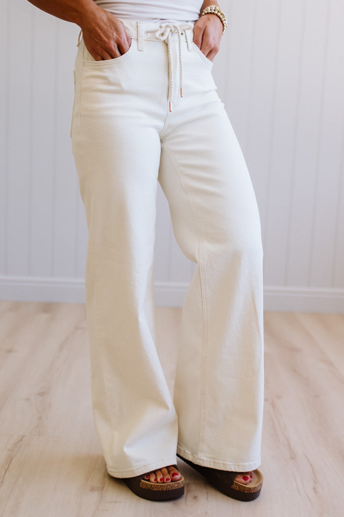 Person wearing cream-colored wide-leg pants on a light wooden floor.
