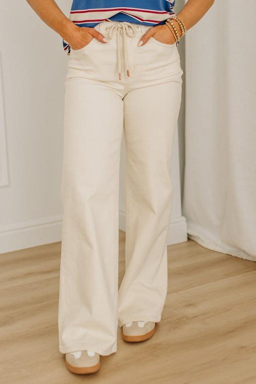 Person wearing white wide-leg pants with a plain background