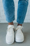 woman wearing creamy white sneakers with a leopard accent on the side.