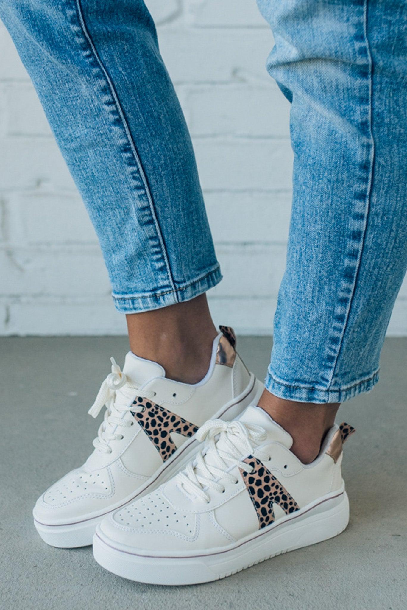 woman wearing creamy white sneakers with a leopard accent on the side.