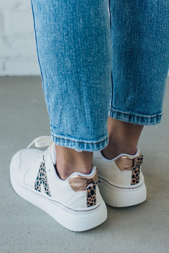 woman wearing creamy white sneakers with a leopard accent on the side.