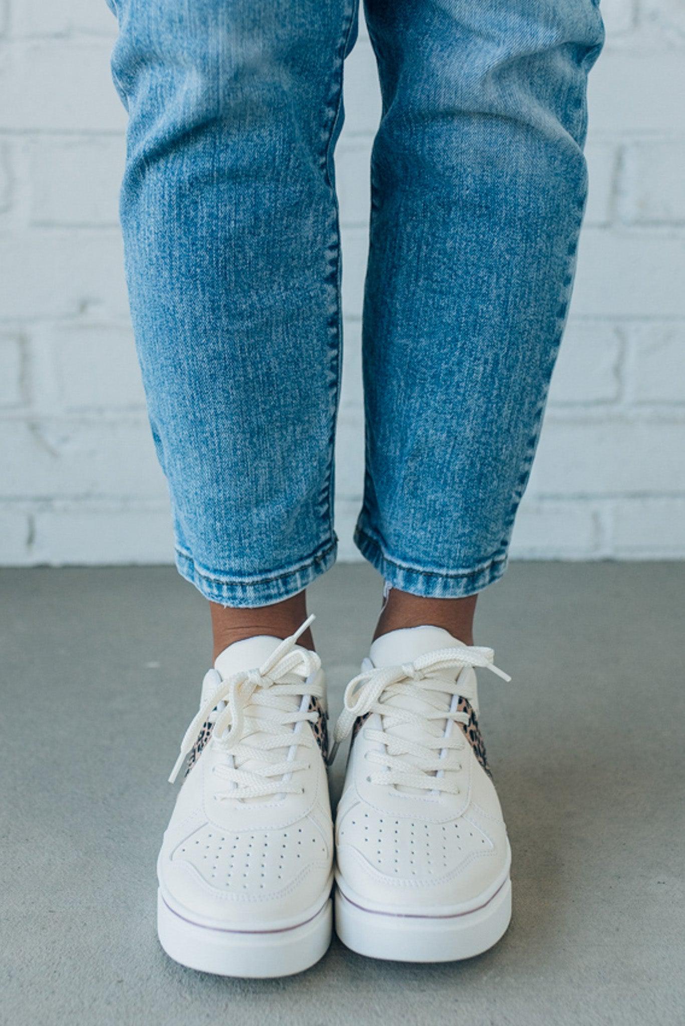 woman wearing creamy white sneakers with a leopard accent on the side.