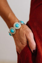 Close up of womans arm with her hand in a pocket of a rust red dress, showing a Western Concho Turquoise Stretch Bracelet